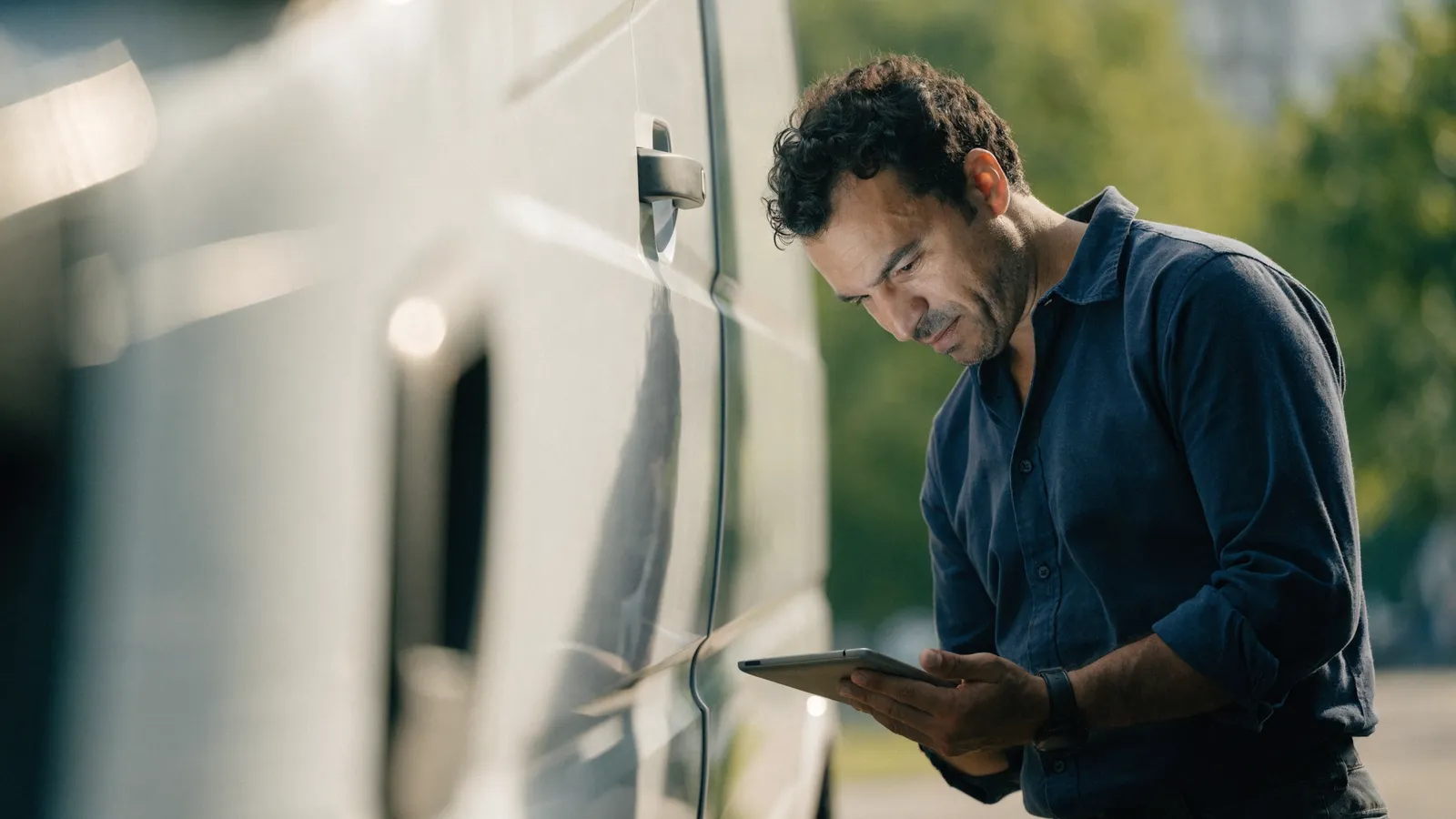 Photo of a pest-control field operator checking FieldRoutes data on a tablet beside a service van, showing AI added without switching CRMs