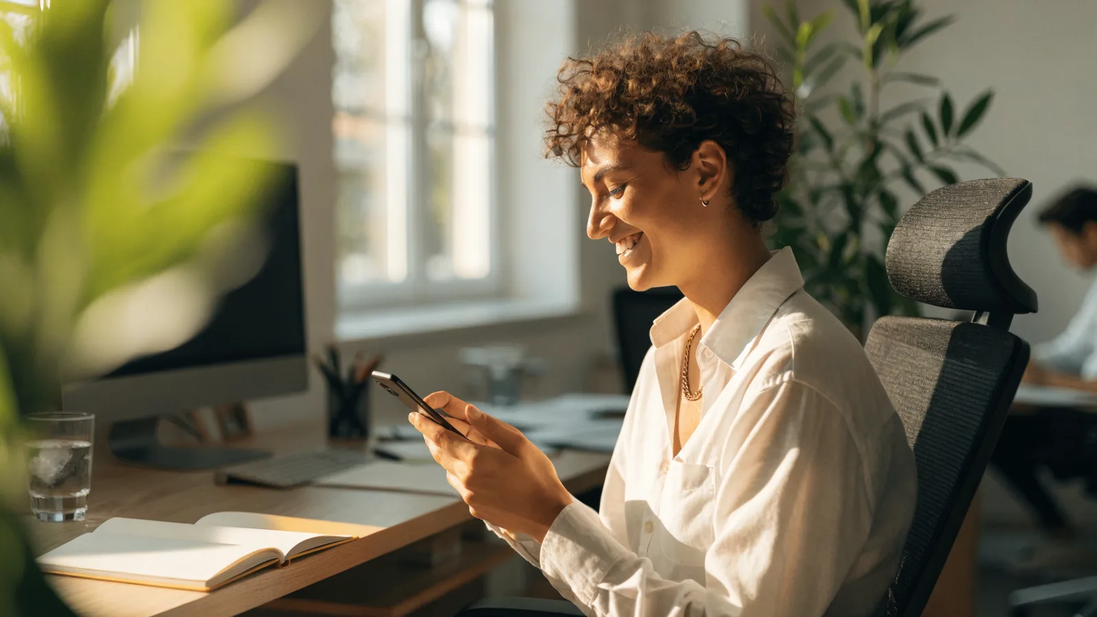 Photo of a smiling pest control office worker reading an automated customer follow-up text message on a smartphone at a desk
