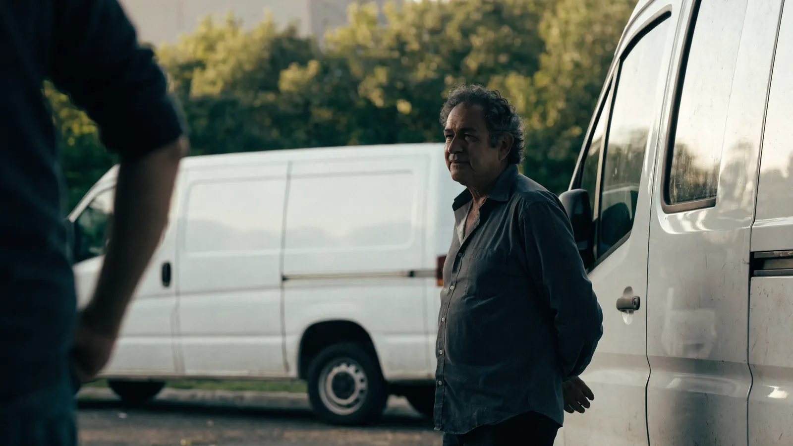 Two pest-control operators talking beside white service vans in a depot lot, weighing GorillaDesk vs FieldRoutes for their growing fleet